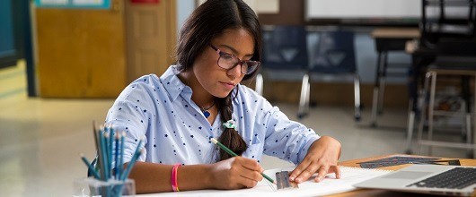 A Girl Scout sitting at a desk writing