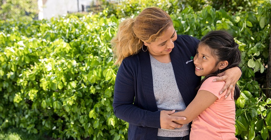 Mom Daughter hugging in front of plants