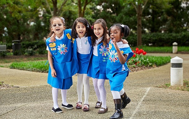 GroupofGirls_group-of-daisy-girl-scouts-kindergarten-first-grade-elementary-school-laughing-smiling-outside-daisy-apron-vest-uniform-petal-badge_610x385