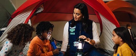 Troop leader with Girl Scouts in a tent outdoors